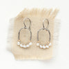 The pearl wrapped mixed metal hoop earrings styled on tan linen
