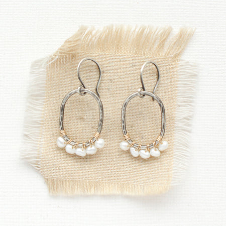 The pearl wrapped mixed metal hoop earrings styled on tan linen