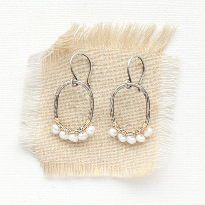 The pearl wrapped mixed metal hoop earrings styled on tan linen