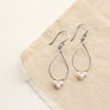 The elegant pearl wrapped teardrop mixed metal hoop earrings styled on tan linen