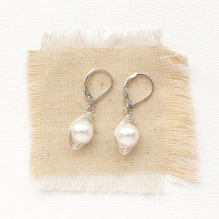 The perfect pearl silver wrapped earrings styled on tan linen