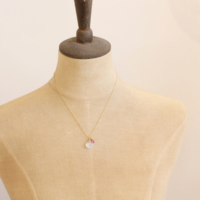 A mannequin wearing the pink sapphire and moonstone charm necklace