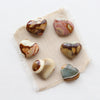 Polychrome jasper heart stones styled on tan linen.