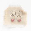 the rhodonite la cloche earrings styled on tan linen