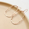 The rose gold organic hoop earrings styled on a tan plate
