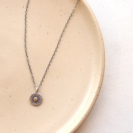 The rustic sun necklace styled on a tan plate