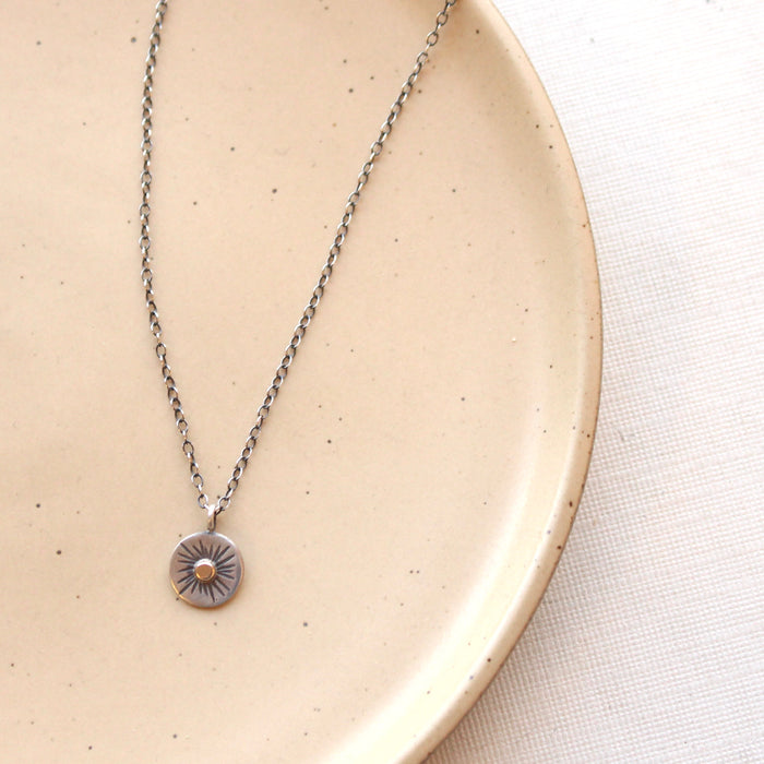 The rustic sun necklace styled on a tan plate