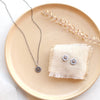The rustic sun post earrings styled on a tan plate with the matching necklace