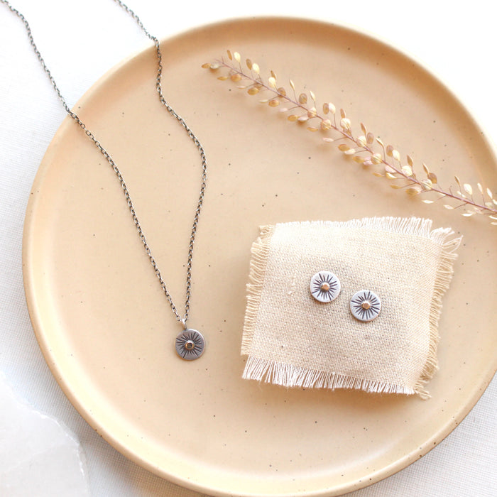 The rustic sun post earrings styled on a tan plate with the matching necklace