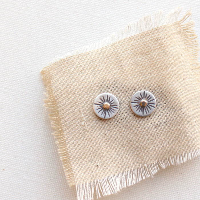 The rustic sun post earrings styled on tan linen