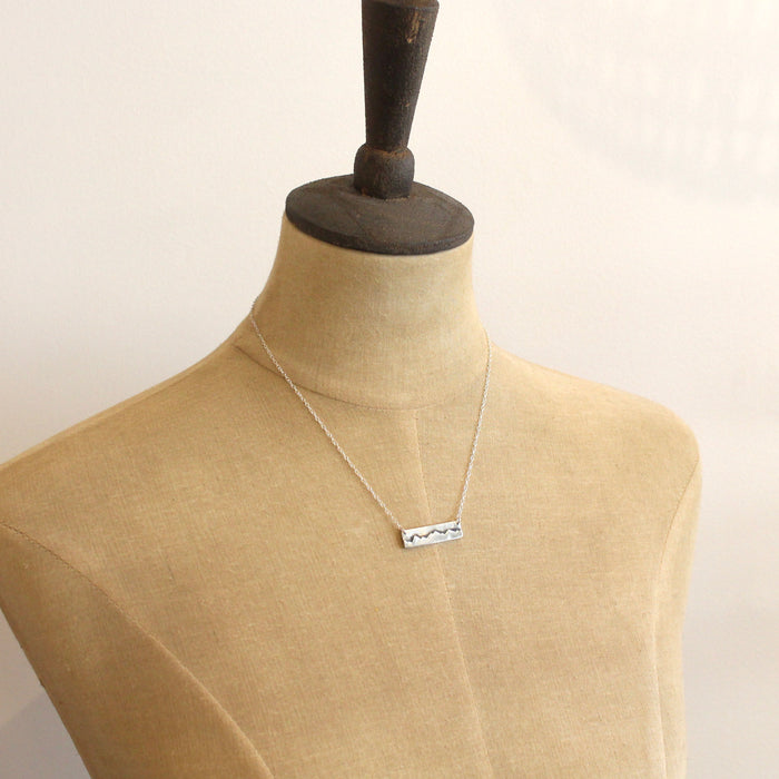 A mannequin wearing the silver layered mountain bar necklace