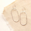 The silver organic hoop earrings styled on tan linen