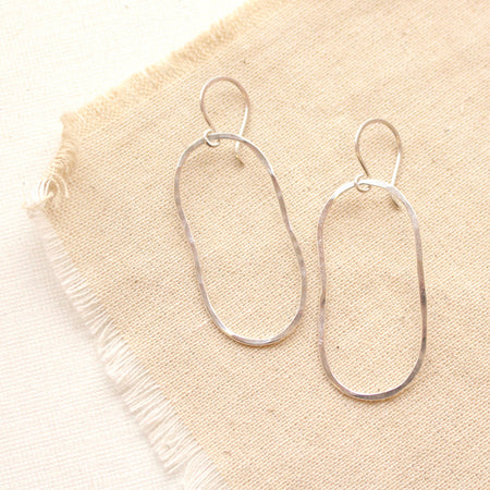 The silver organic hoop earrings styled on tan linen