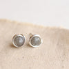The silver wrapped labradorite post earrings styled on tan linen