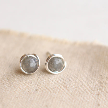 The silver wrapped labradorite post earrings styled on tan linen