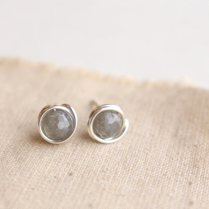 The silver wrapped labradorite post earrings styled on tan linen