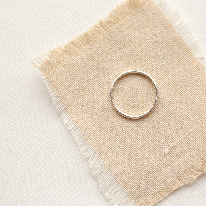 The silver stacking ring styled on tan linen
