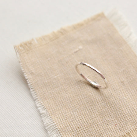 The silver stacking ring styled on tan linen