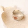 The stamped bee band ring styled on tan linen