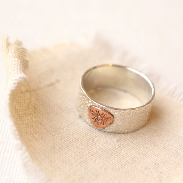 The stamped bee band ring styled on tan linen