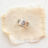 The stamped feathered wide band ring styled on tan linen