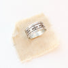 The stamped linear and cross band ring is styled on tan linen