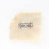 The stamped linear and cross band ring is styled on tan linen