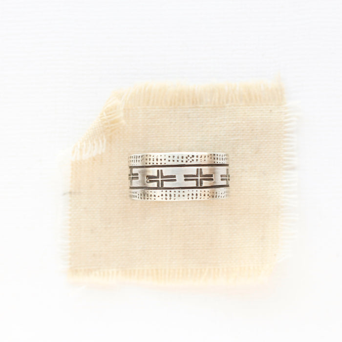 The stamped linear and cross band ring is styled on tan linen