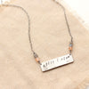 The backside of the still i rise bar necklace showing the words
