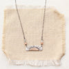 The still i rise bar necklace styled on tan linen