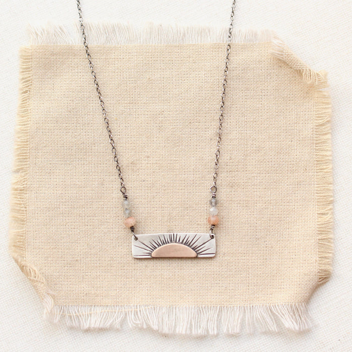 The still i rise bar necklace styled on tan linen