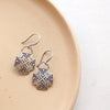 The southwest stamped silver sun cross earrings styled on a tan plate