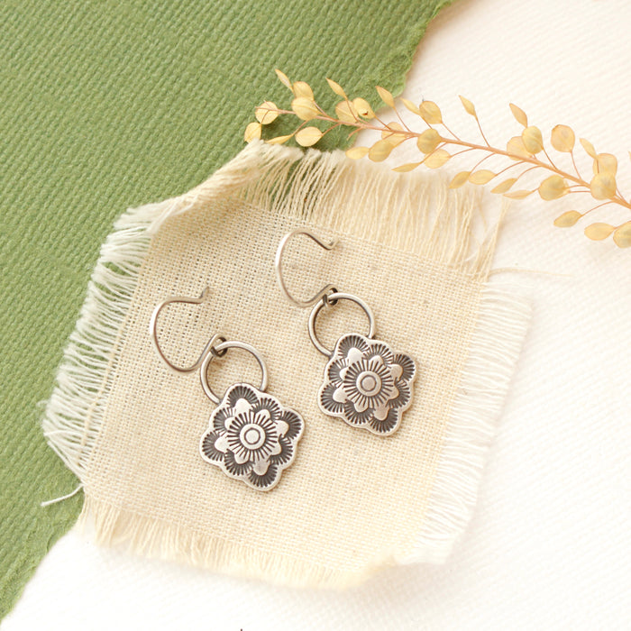 The talara bloom earrings styled on tan linen with dried grass