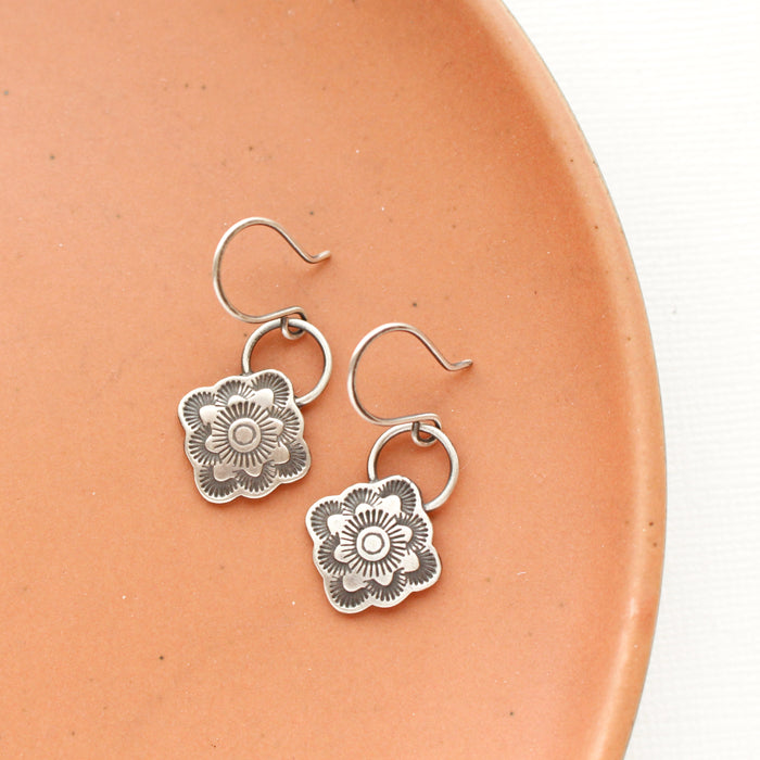 The talara bloom earrings styled on an orange plate