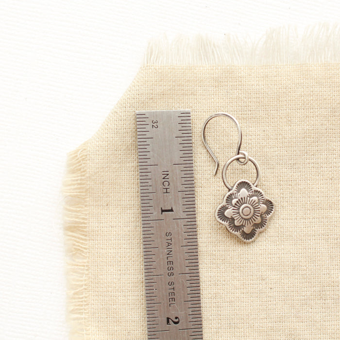 A talara bloom earring next to a ruler for size reference