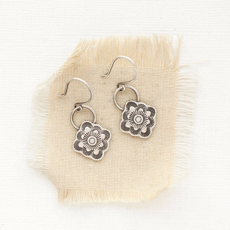 The talara bloom earrings styled on tan linen