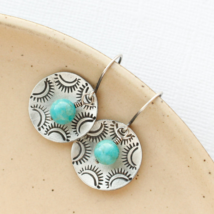 The turquoise jolie earrings styled on a tan plate