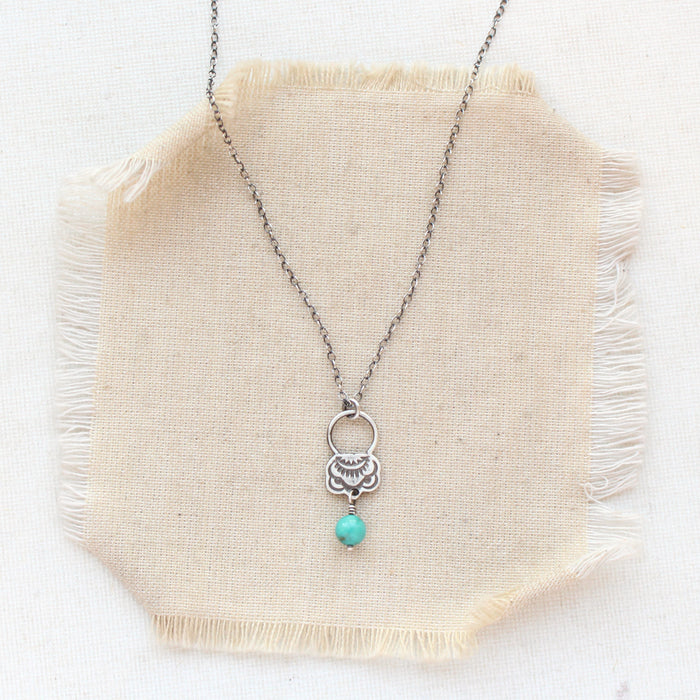 The turquoise jolie necklace styled on tan linen