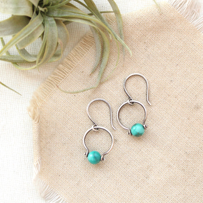 The turquoise la cloche earrings styled on tan linen with an air plant