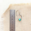 A turquoise la cloche earring next to a ruler for size reference