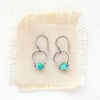 The turquoise la cloche earrings styled on tan linen