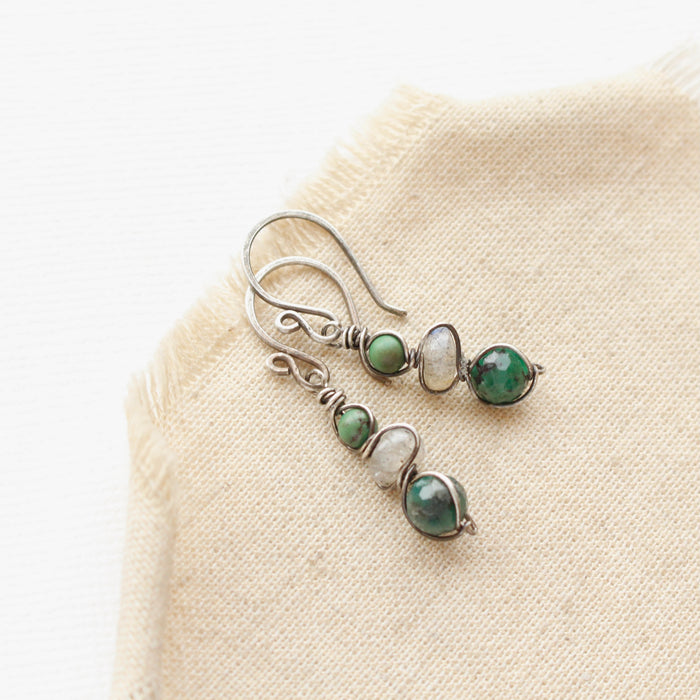 the stacked turquoise, labradorite, & emerald earrings styled on tan linen