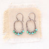 The turquoise wrapped hoop earrings styled on tan linen