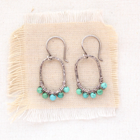 The turquoise wrapped hoop earrings styled on tan linen