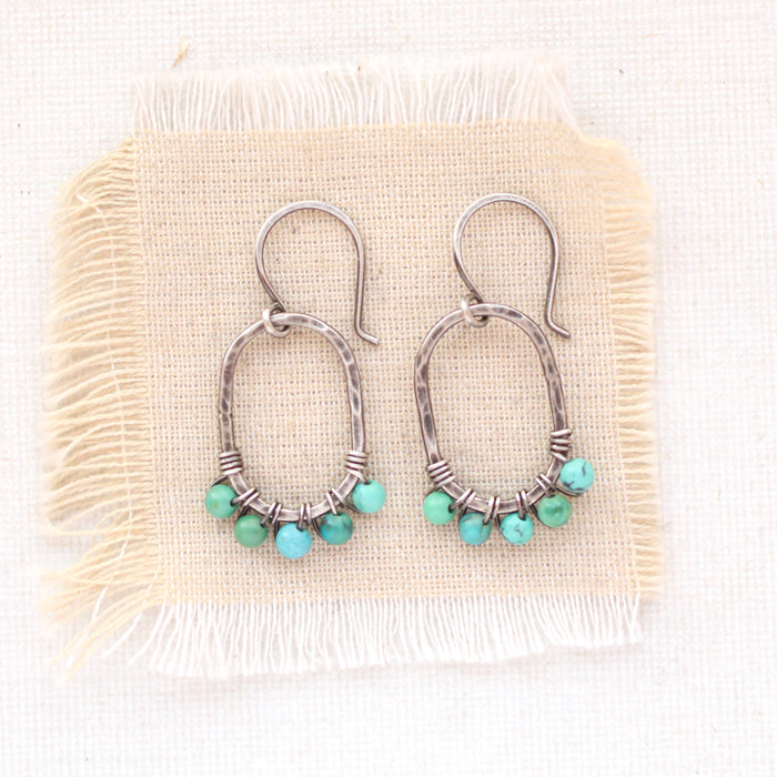 The turquoise wrapped hoop earrings styled on tan linen